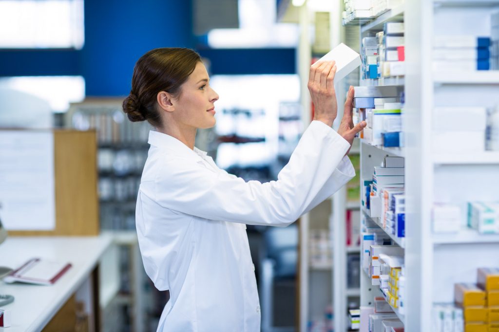 Pharmacist checking medicine in shelf