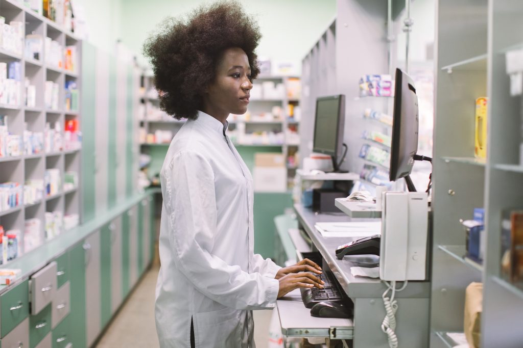 Certified Pharmacy Technician working in hospital, CPhT Young African American pharmacist using computer reading medication