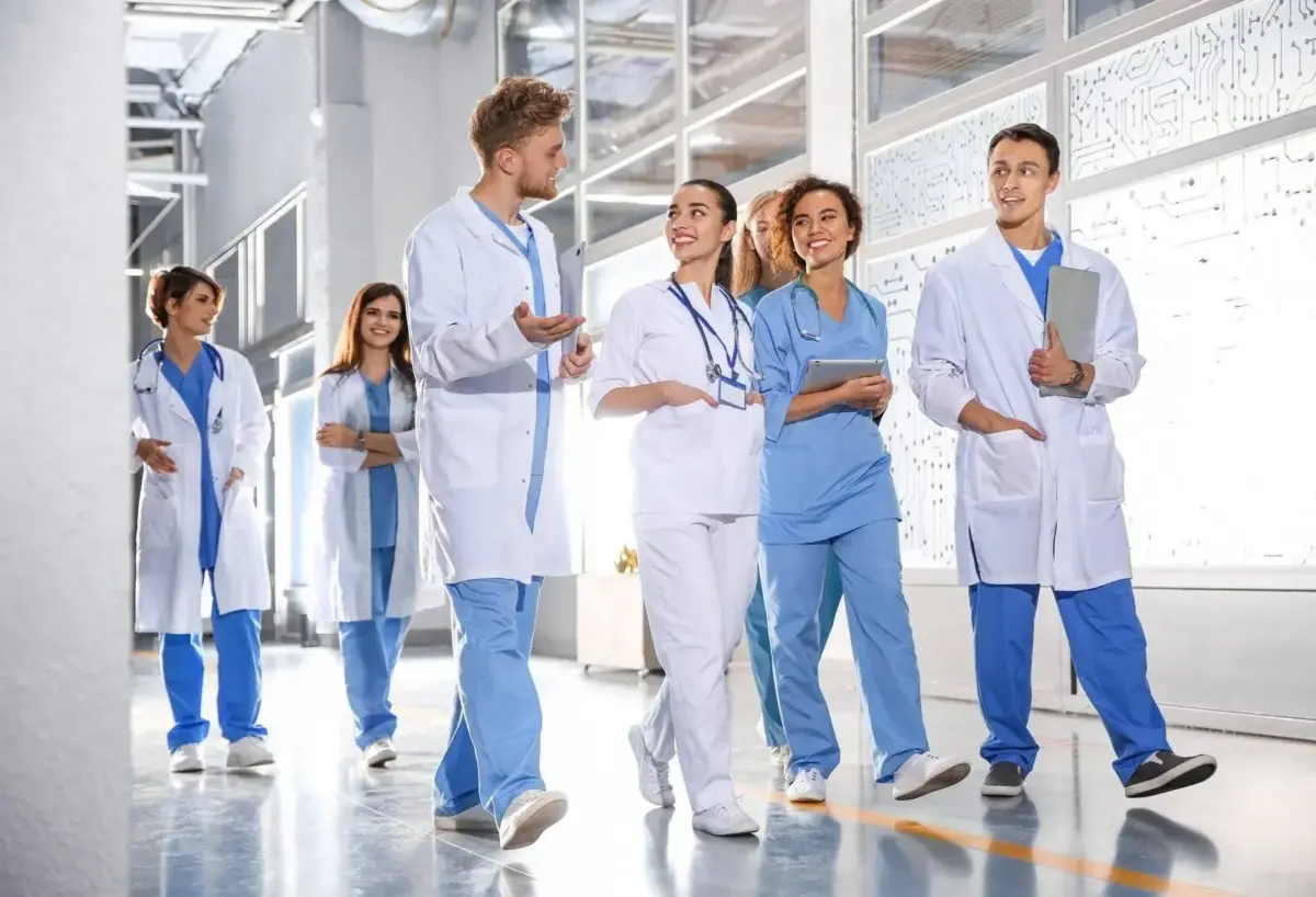 Healthcare professionals in scrubs and lab coats walking down a hospital corridor