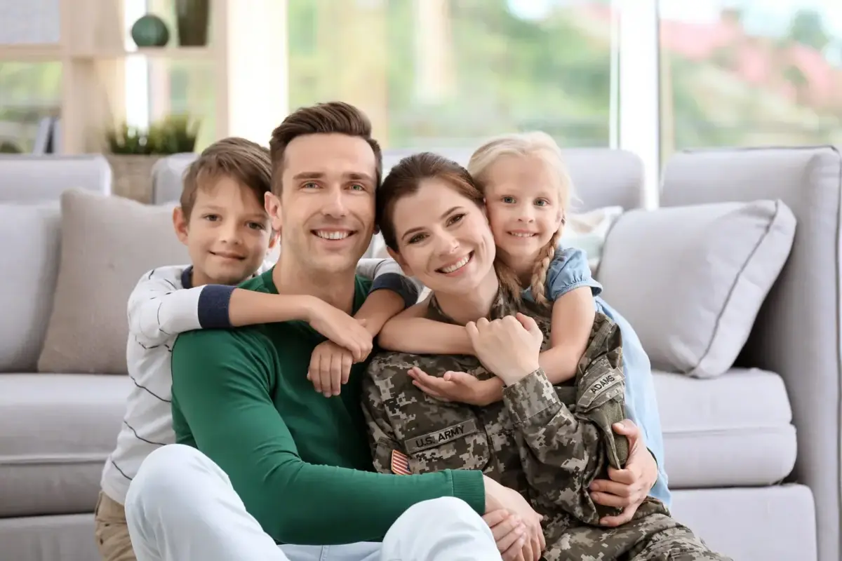 Two adults and two children together at home, one adult wearing a military uniform.